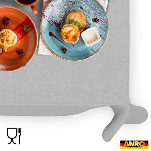 Hellgraue Tischdecke aus Stoff mit feiner Textur, gedeckt mit Frühstückstellern, Pfannkuchen und Tasse. Lebensmittelecht. ANRO Logo.