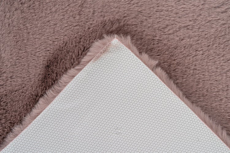 Detailansicht der rutschhemmenden Unterseite eines rosa Kunstfell-Teppichs.