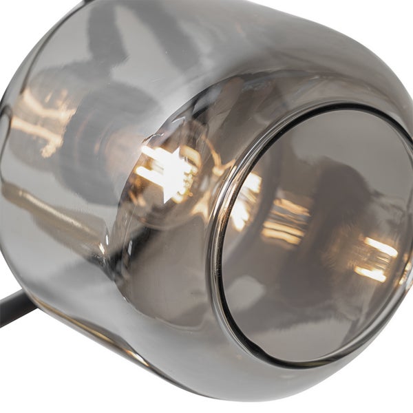 Nahaufnahme eines abgerundeten Lampenschirms aus Rauchglas mit einem leuchtenden Filament-Leuchtmittel im Inneren.