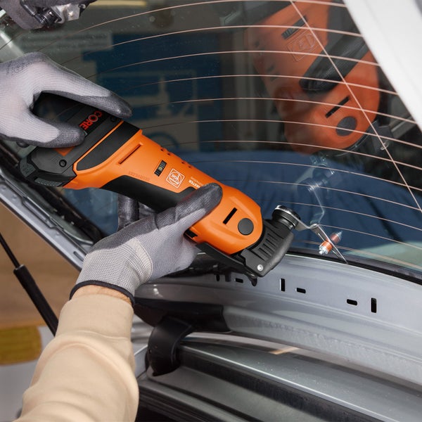 Ein Mann schleift eine Wand mit einem Langhalsschleifer in einem Raum mit einem Staubsauger.