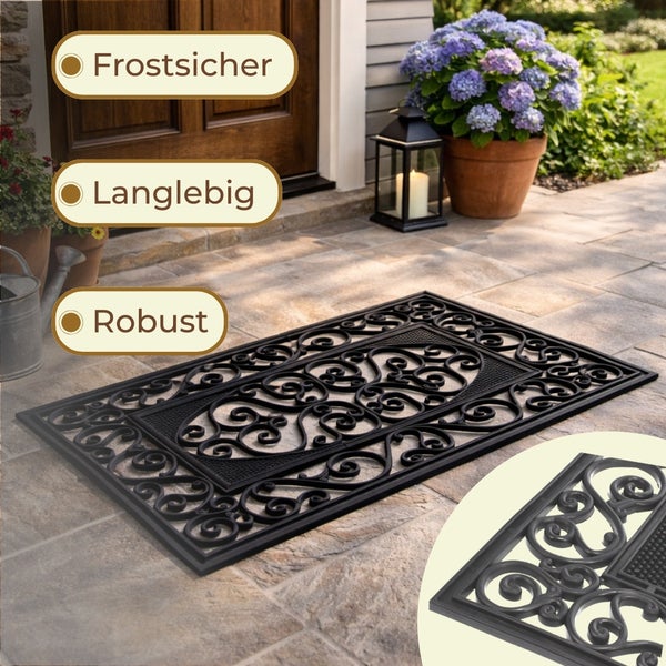 Schwarze Fußmatte aus Gummi mit Ornamentmuster vor einer Haustür
