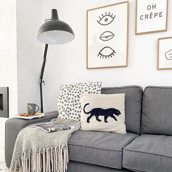 Wohnzimmer mit grauem Sofa, Kissen, Decke und Stehlampe