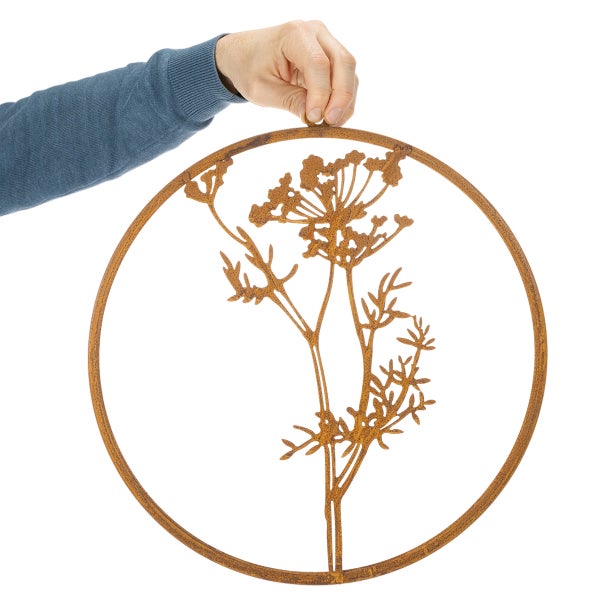 Runde Wanddekoration aus Metall in Edelrost-Optik mit einem Blumenmotiv.