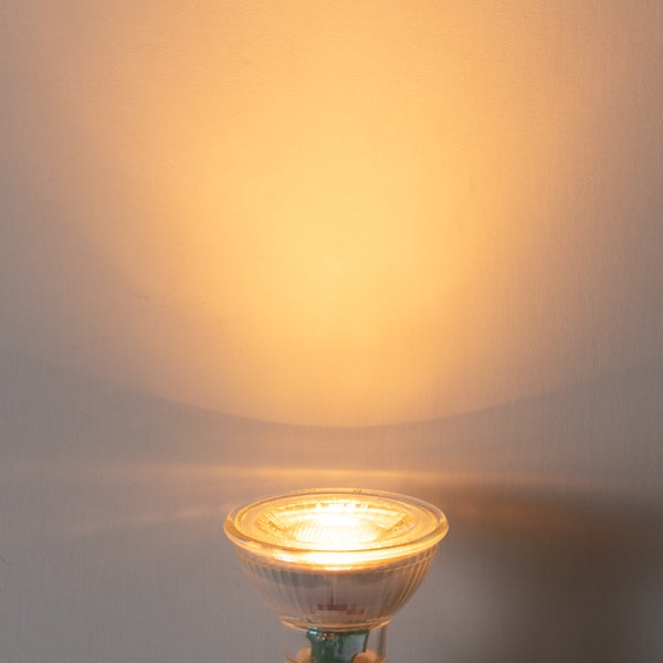 Eingeschaltetes LED-Leuchtmittel mit warmweißem Lichtschein an einer Wand.