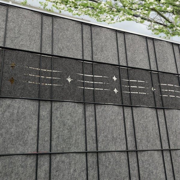 Nahaufnahme einer grauen Lärmschutzwand mit Sternmotiven in einem schwarzen Rahmen.