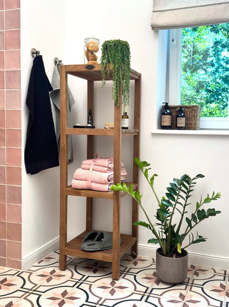 Badezimmer mit Holzregal, Handtüchern, Pflanzen und Dekorationsartikeln für eine helle und organisierte Atmosphäre.