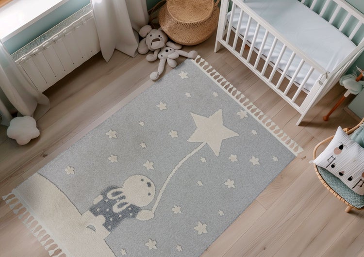 Kinderteppich mit Hasenmotiv und Sternenmuster in einem hell eingerichteten Kinderzimmer mit Gitterbett und Holzfußboden.