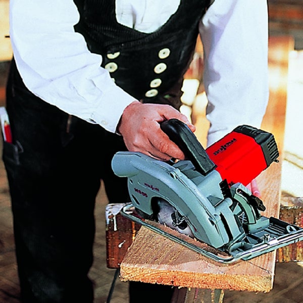 Handwerker beim Zuschneiden eines Holzbretts mit einer elektrischen Handkreissäge
