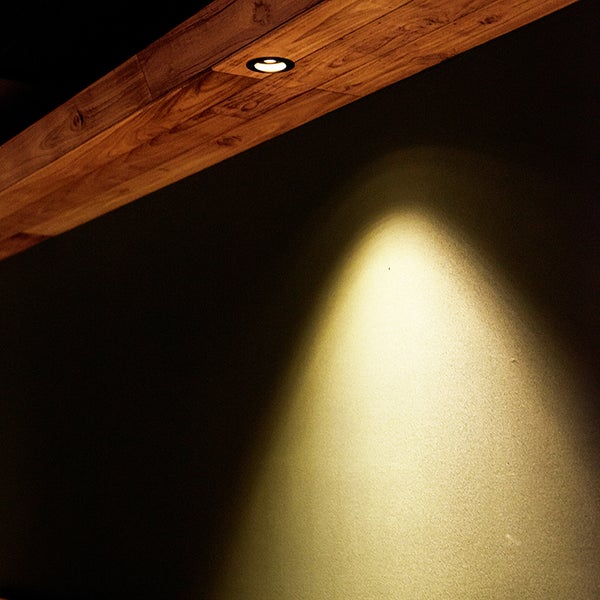 Deckenleuchte aus Holz beleuchtet eine Wand.