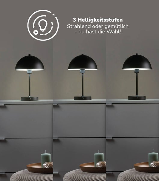 Schwarze Tischleuchte aus Metall mit drei Helligkeitsstufen auf einer Kommode.