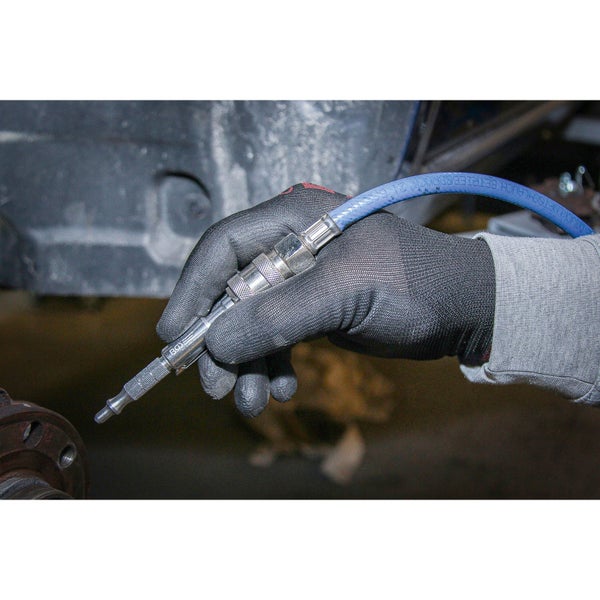 Eine Hand mit Arbeitshandschuhen hält eine Druckluftpistole mit Luftschlauch.