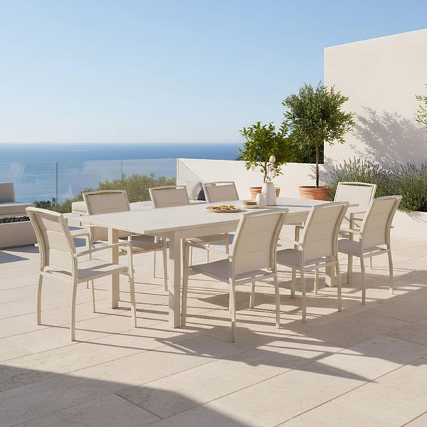Großes Gartenmöbel-Set bestehend aus Tisch und acht Armlehnstühlen auf einer hellen Terrasse mit Meerblick.