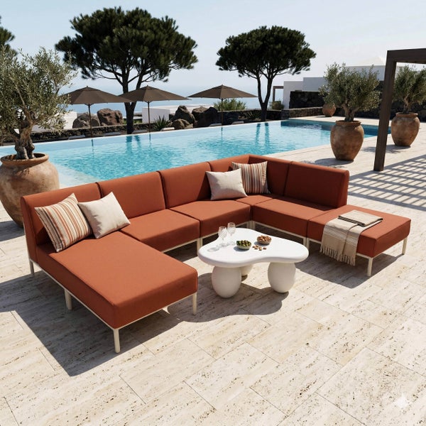 Modulares Garten-Lounge-Set mit terracottafarbenen Polstern und weißem Gestell auf einer Terrasse am Pool mit Beistelltisch und Dekoration.