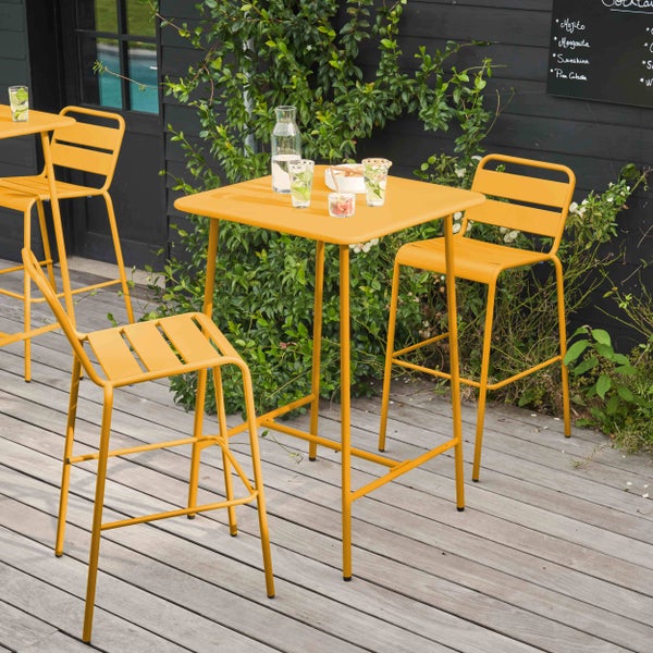 Gelbes Garten-Bar-Set aus Metall bestehend aus einem quadratischen Stehtisch und zwei Barhockern mit Rückenlehne.