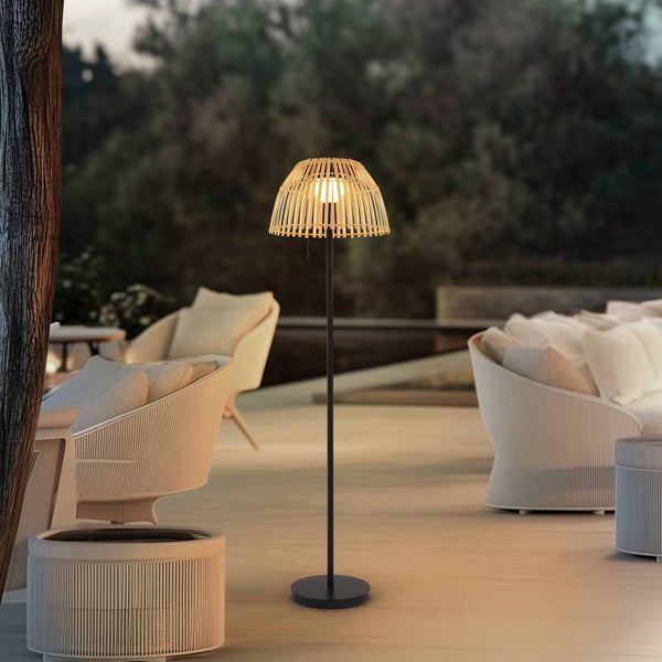 Stehleuchte für den Außenbereich mit Schirm aus Bambusgeflecht auf einer Terrasse mit Loungemöbeln.