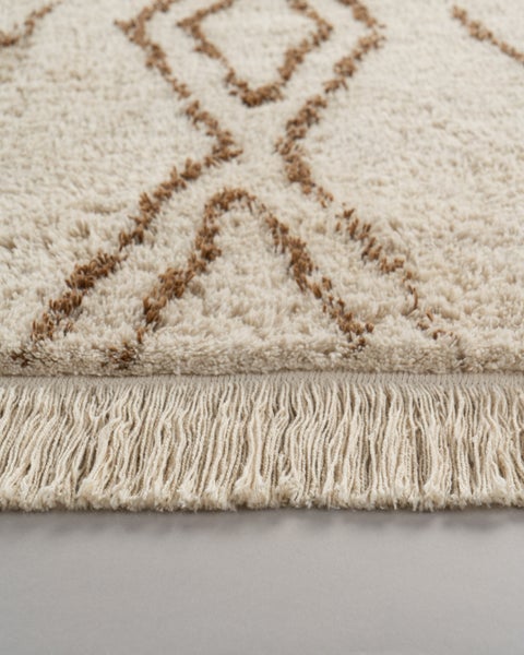 Hochflor-Shaggy-Teppich mit Fransen und braunem geometrischem Muster auf hellem Grund.