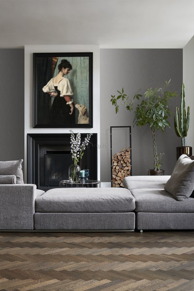 Wohnzimmer mit grauer Couch, Kamin, Gemälde und Pflanzen