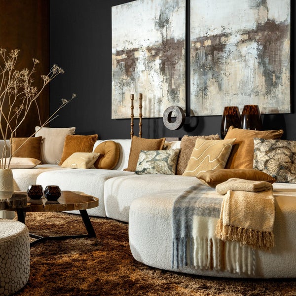 Wohnzimmer mit modularem Sofa, Kissen, Decke, Couchtisch und abstraktem Wandbild