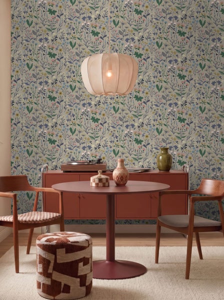 Modern eingerichteter Raum mit floraler Tapete, rundem Tisch, Holzstühlen und Sideboard im Vintage-Stil.