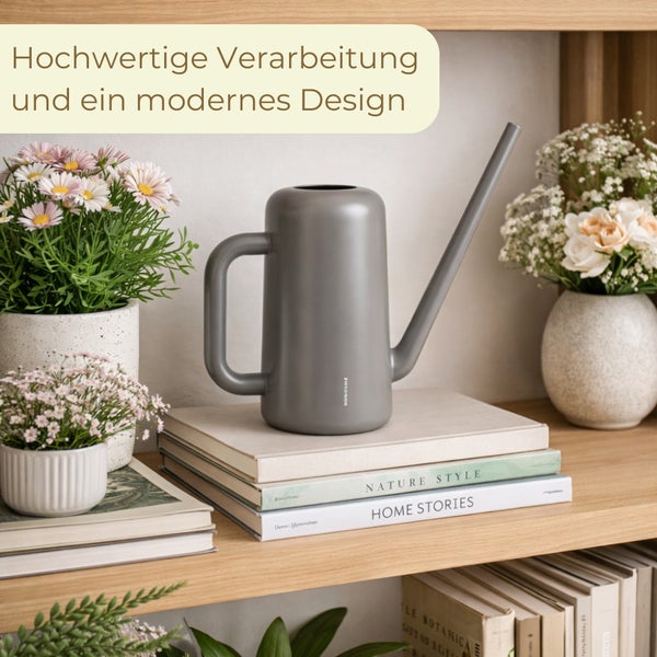 Moderne Gießkanne in Grau mit langem Ausguss, platziert auf Büchern in einem Holzregal neben Blumentöpfen.