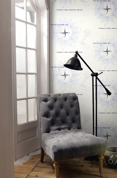 Einrichtungsszene mit Sessel, Stehlampe und Tapete mit Weltkartenmuster