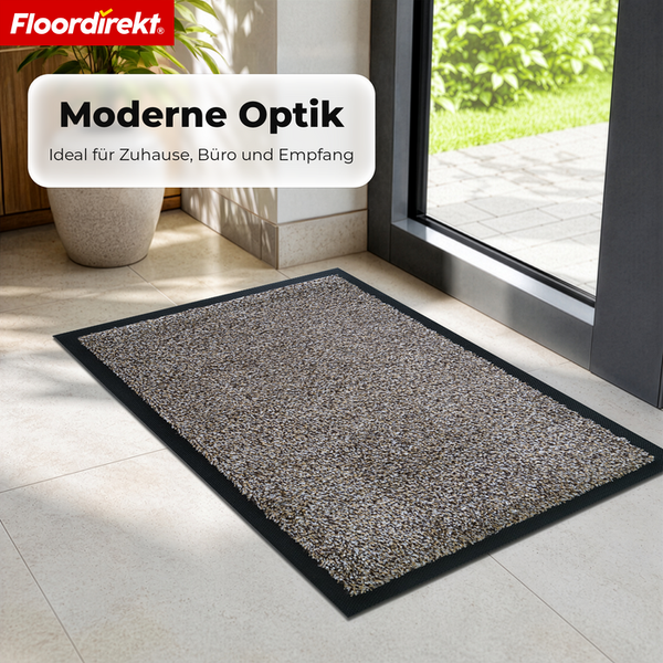 Floordirekt Logo. Moderne Schmutzfangmatte mit melierter Oberfläche und schwarzem Rand auf Fliesenboden vor einer Glastür. Hell und geordnet.