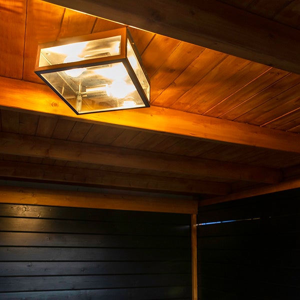 Quadratische Außen-Deckenleuchte aus Metall und Glas an einer Holzdecke mit warmem Licht.
