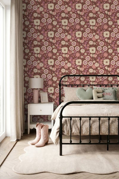Vliestapete mit Retro-Blumenmuster in einem hellen Schlafzimmer mit Metallbett, Nachttisch und Teppich.