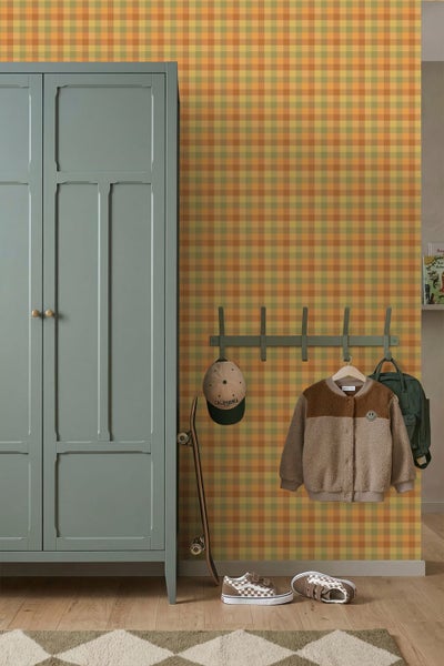 Tapete mit Karomuster in Gelb, Orange und Grün an einer Wand mit Schrank, Garderobe und Skateboard in einem ordentlichen Zimmer.