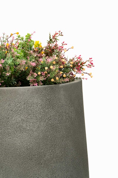 Grauer, strukturierter Pflanzkübel mit Kunstblumen in Rosa und Gelb.