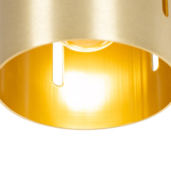 Nahaufnahme einer goldenen Zylinderleuchte mit eingeschalteter Glühbirne