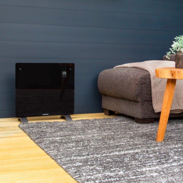 Ein elektrischer Konvektor Heizstrahler von Vonroc mit Glasfront und digitalem Display steht auf einem Holzboden in einem modern eingerichteten Raum.