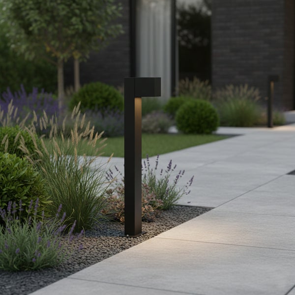 Moderne schwarze Pollerleuchte zur Beleuchtung eines Gartenwegs mit Gräsern und Lavendel.