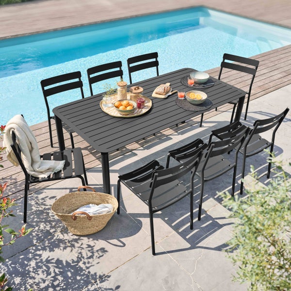 Modernes Gartenmöbel-Set bestehend aus einem großen rechteckigen Esstisch und passenden Stühlen aus Metall auf einer Terrasse am Pool.