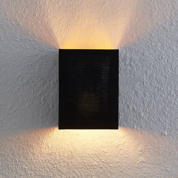 Rechteckige Wandleuchte in Schwarz mit Up-and-Down-Lichteffekt an einer strukturierten Wand.