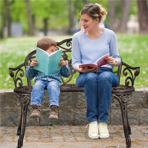 Mutter und Kind lesen auf einer verzierten Gartenbank Bücher.