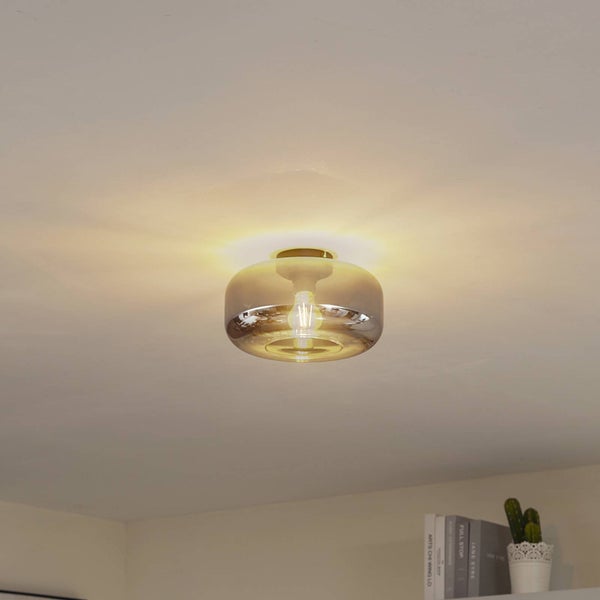 Moderne runde Deckenleuchte mit Schirm aus Rauchglas und goldfarbenem Sockel, eingeschaltet mit warmem Licht.