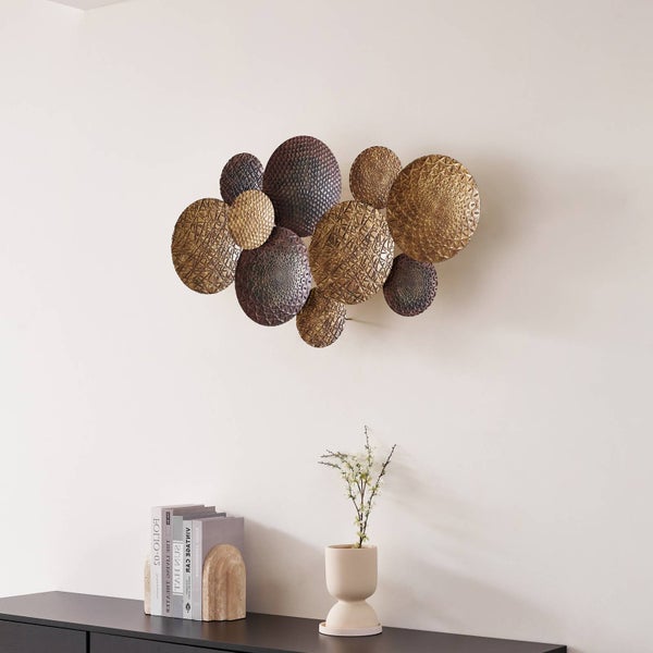 Moderne Wanddekoration aus runden Metallelementen mit verschiedenen Texturen und Mustern über einem Sideboard.