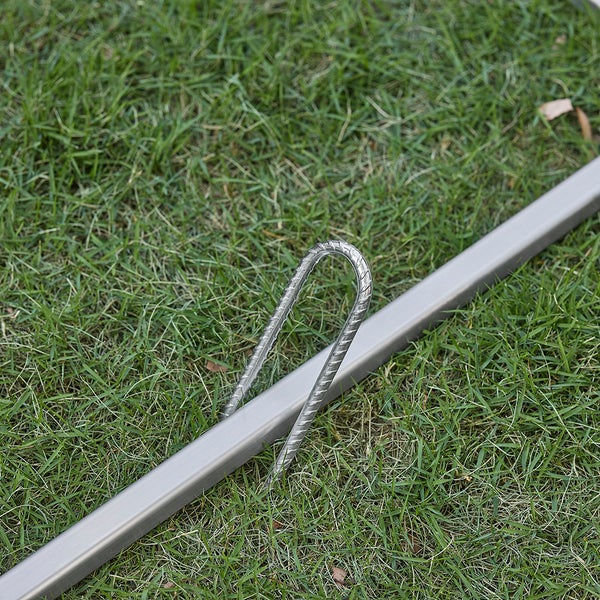 Detailansicht eines Stahlherings zur Befestigung im Boden neben einem Rahmen.