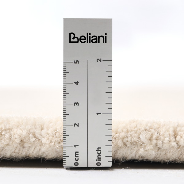 Beliani Logo auf einem Lineal zur Messung der Florhöhe eines Hochflor Teppichs in Zentimeter und Zoll.