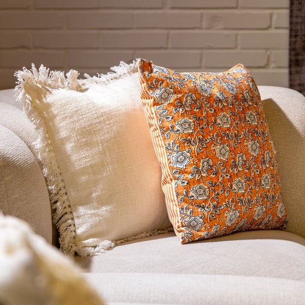 Dekorative Kissen mit Fransen und Blumenmuster auf einem Sofa.