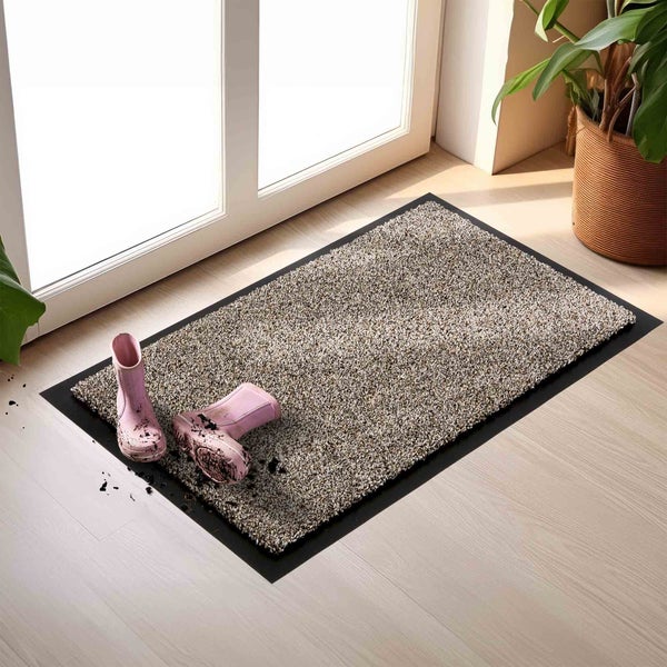 Schmutzfangmatte mit schwarzen Rändern und ein Paar Gummistiefel davor.