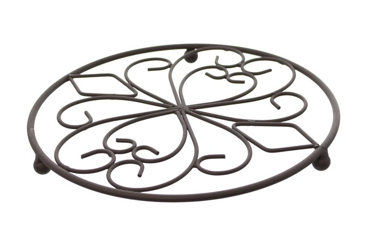 Szene mit drei Untersetzern aus Metall, Topf und Geschirr auf einem Holztisch.