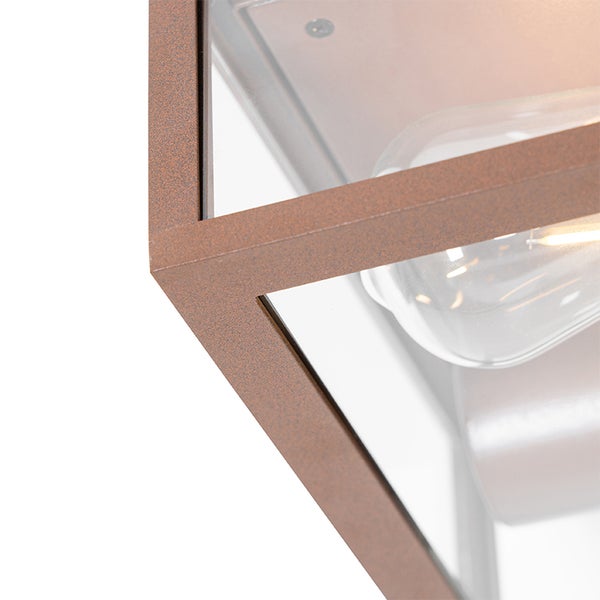 Nahaufnahme einer quadratischen Außenwandleuchte mit rostfarbenem Metallrahmen, Klarglasscheiben und sichtbarem Leuchtmittel.