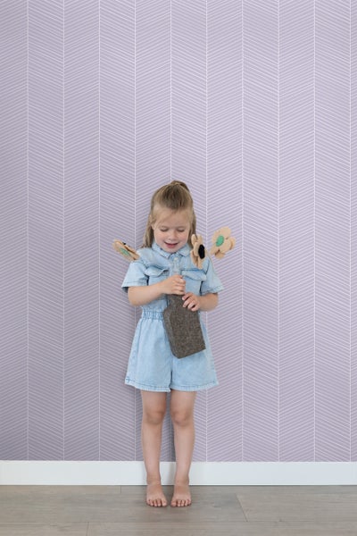 Mädchen mit Spielzeug vor Wandtapete mit Zickzackmuster