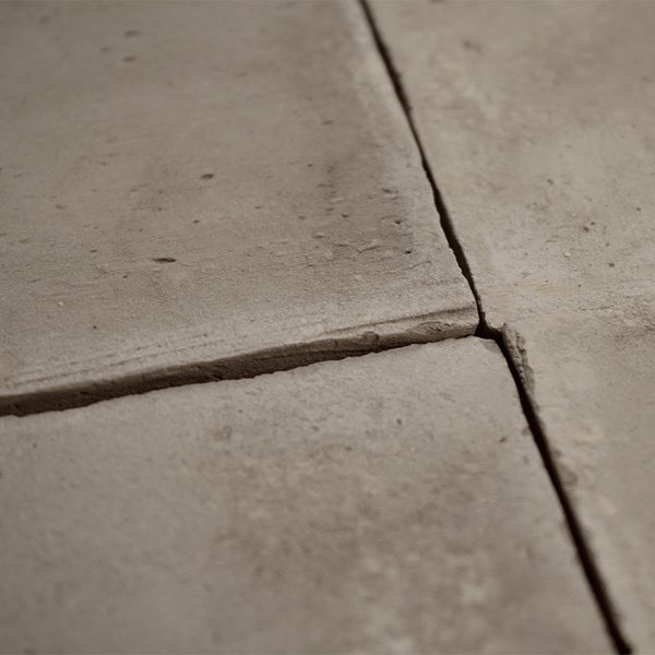 Nahaufnahme von quadratischen Betonplatten mit rustikaler Struktur und sichtbaren Fugen für die Gartengestaltung.