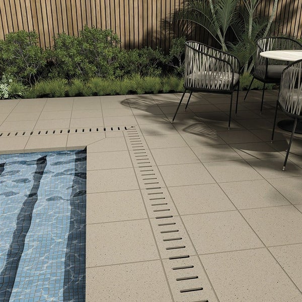 Terrassengestaltung mit quadratischen Feinsteinzeugfliesen rund um einen Pool mit Entwässerungsrinne im Gartenbereich.