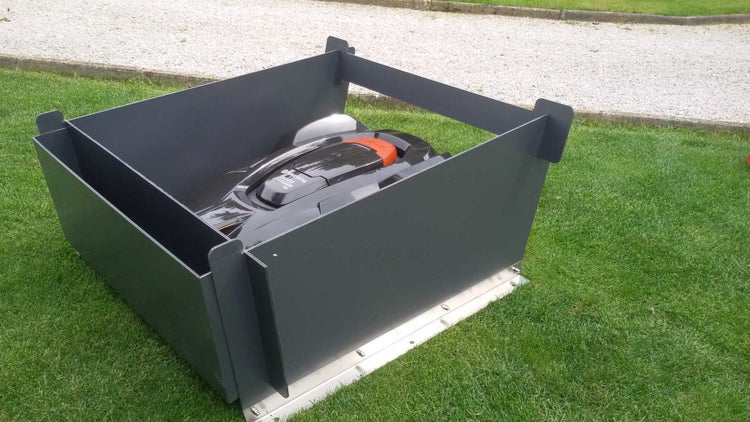 Mähroboter mit Garage auf Rasenfläche