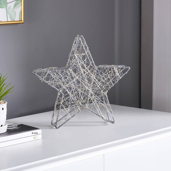 Dekorativer LED-Drahtstern aus silberfarbenem Metall mit integrierter Lichterkette auf einem weißen Sideboard.