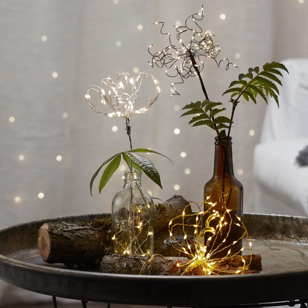 Dekoration mit LED-Drahtlichtern in Flaschen auf einem Tablett mit Holzstücken